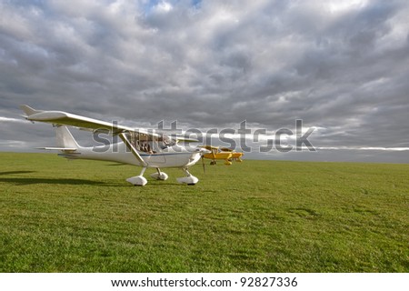 light weight planes on a grass field against a clouds landscape