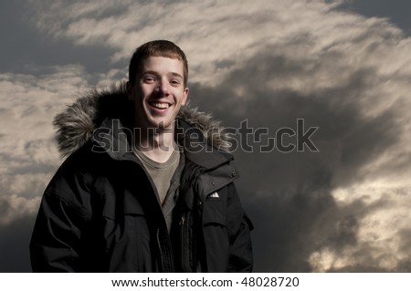 Fashion modeling portrait wearing fur hooded parka coat with moody sky.