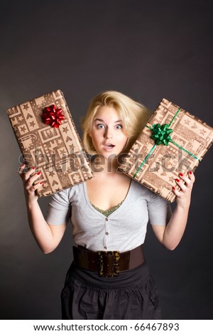 Surprised woman holding two gift box on black background