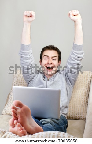 Top view of happy guy sitting on couch and working on laptop