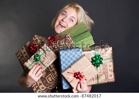 A lovely woman holding a many gift boxes on black background