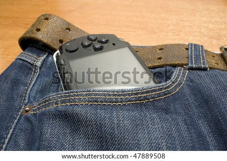 portable electronic game player in the pocket of a demin jeans