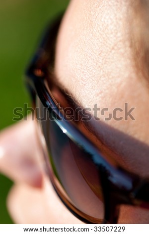 A closeup of sunglasses on a woman\'s face, looking down towards her nose.