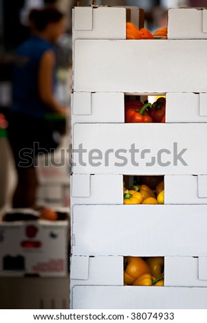 Focus on stacked boxes full of colorful peppers at a local outdoor farmers market.