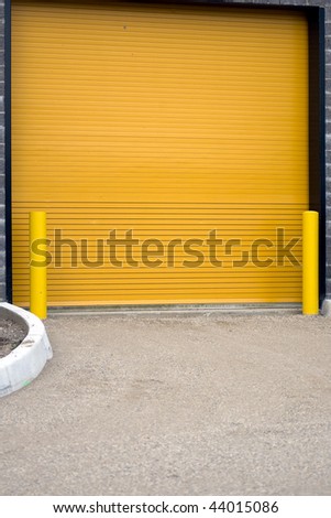 A colorful industrial garage door, with yellow barriers on either side.