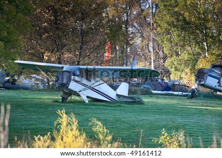 A plane graveyard in the country, showing many pieces of old prop planes in a field.