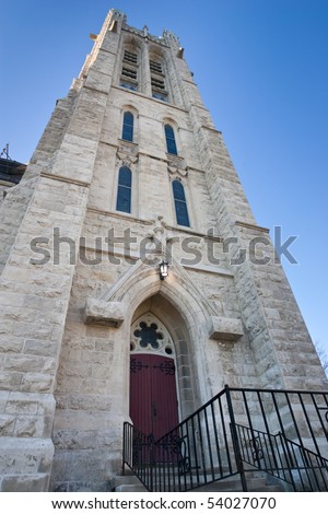 Looking up at the side of an old church, focus on a side door, with black railing leading up to it.  Church of our Lady, Guelph, Ontario, Canada