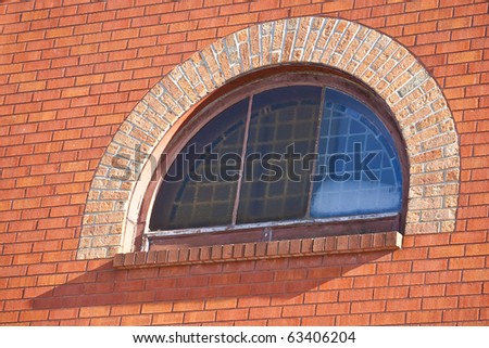 A brick wall, focus on a half moon window.