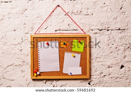 Cork bulletin board with notes, business cards and instant photo cards hang on the wall