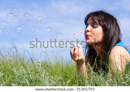 young girl starts up soap bubbles on a background of the blue sky