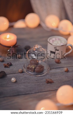 on wooden table lit garland and candle in a cup of coffee and chocolate