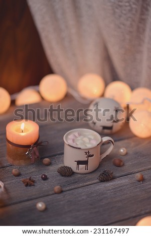 on wooden table lit garland and candle in a cup of coffee and nuts