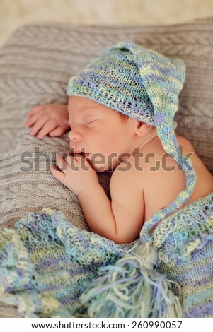 in bed sleeping baby in a blue cap with a large bubo