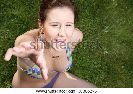 Beautiful woman reaching for something. Grass background.