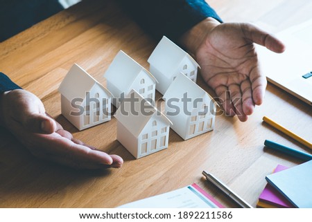 Business property,real estate and investment concepts with investor and white model house on desk background.