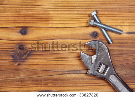 Screws and spanner on wood board. Background pic with screws and spanner at the right. Space for your text on the left.
