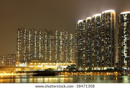Apartment buildings at night with ships and boats at the foreground.