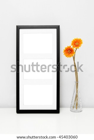 Picture Frame for Home Decoration. Potted sunflowers and a black picture frame on white table against a white wall.