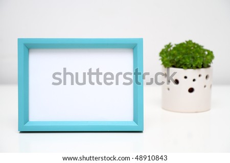 Picture Frame for Home Decoration.. Selective focused light blue photo frame on white background. Potted plant at the back.