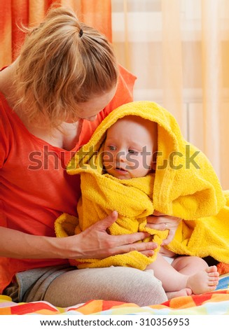 Mother with adorable pretty baby, kid covered with bath towel. After shower. Happy family portrait.