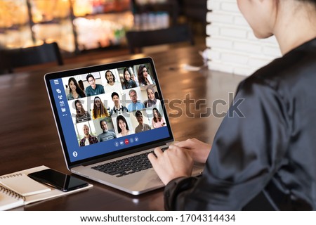 Back view of young asian business woman work remotely at home video conference remote call to corporate group. Meeting online,videocall, group discuss online concept with screen of teamwork on laptop.