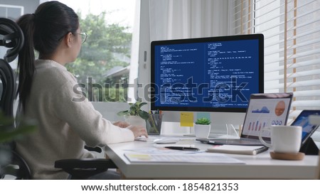 Back rear view of young asian woman, freelance data scientist work remotely at home coding programing on Big data mining, AI data engineering, IT Technician Works on Artificial Intelligence Project.