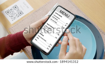 Hand's customer scan QR code for online menu service at table in restaurant during pandemic coronavirus. New normal contactless technology lifestyle protection coronavirus pandemic in restaurant