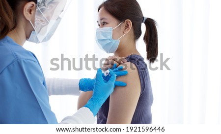 Practitioner vaccinating woman patient in clinic. Doctor giving injection to adult woman at hospital. Nurse holding syringe and inject Covid-19 or coronavirus vaccine.Injection covid vaccine concept.