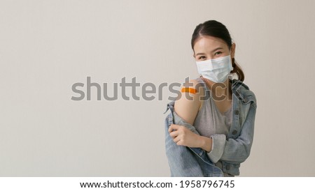 Young attractive beautiful asia female or teenage receive covid-19 anti virus vaccine in campaign vaccination safe life happy smile cheerful with blue, yellow, pink bandage on arm with copy space.