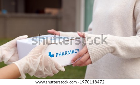 Asian female patient receive medication package box free first aid from pharmacy hospital delivery service at home wear glove in telehealth, telemedicine healthcare insurance online concept.
