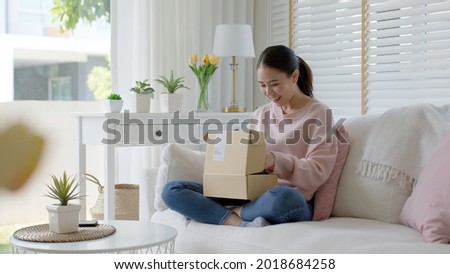 Young happy asia people teen girl smile enjoy unbox post mail sit relax at home comfort sofa couch feel joy amazed awe wow in omni channel fast send parcel via online sale shop store e-commerce order. Foto stock © 