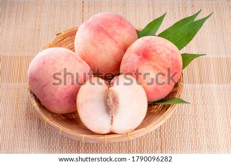 Fresh White Peach fruits with leaves on bamboo mat, Korean white peach in Bamboo basket on wooden bamboo table.