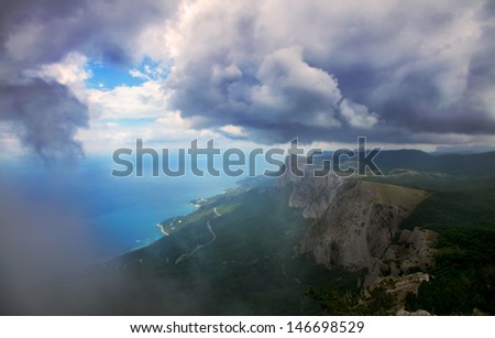 Landscape, high mountains in the clouds towering above the sea