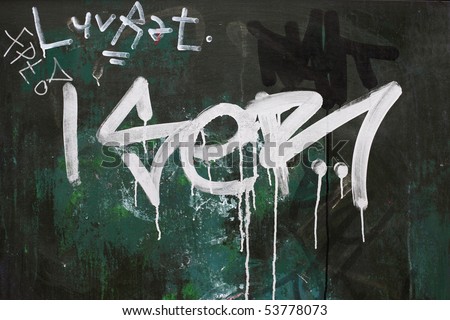 A dark green surface with a rough graffiti tag