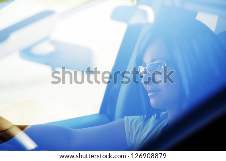 Pretty woman driving a car, mysterious look behind the glass
