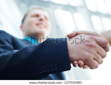 Business people shaking hands. Bright modern building background.