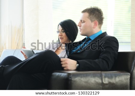 Young business people having meeting at office sitting on sofa talking
