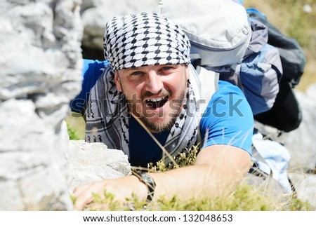 Young white man climbing a steep wall in mountain, rock climbing and hiking extreme sport