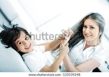 Young mom and her little son together on couch in living room
