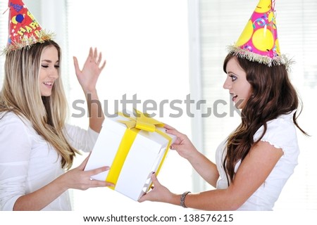 Two beautiful caucasian girls celebrating birthday wearing holiday hats