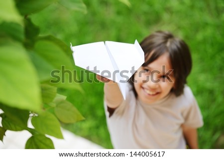 Boy holding a paper airplane dreaming about flying and traveling