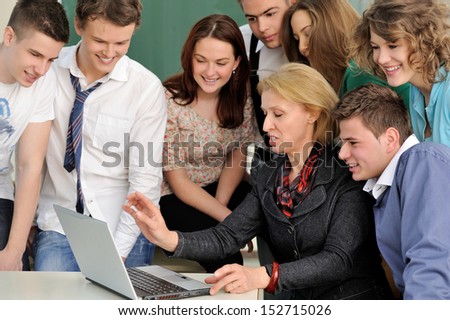 Teacher in a classroom giving her students a lecture on laptop