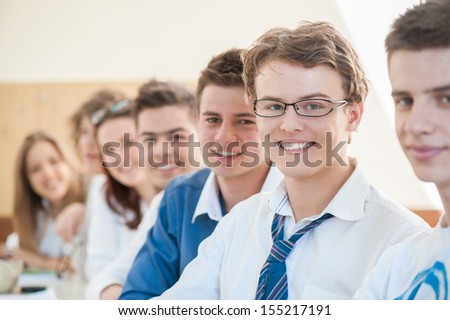 Joyful group of teenagers posing in a classroom