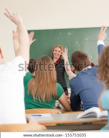 Cheerful teacher in a classroom looking at asking students
