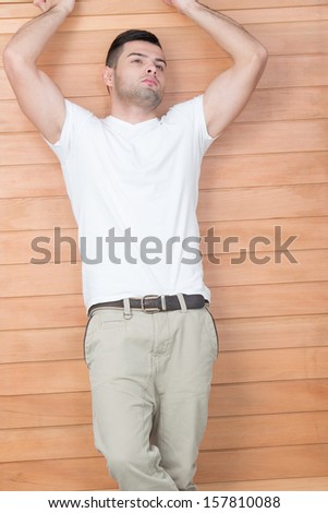 Handsome young male model leaning on wooden frame