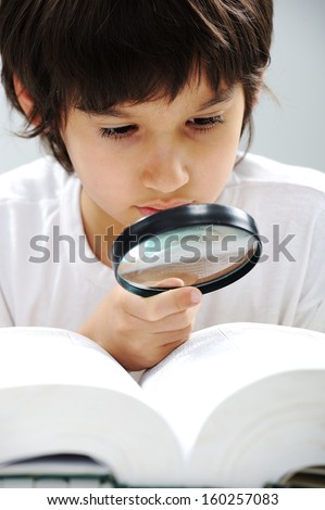 Geeky little boy studying and wearing glasses