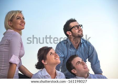 Group of smiling corporate people sitting outside looking up