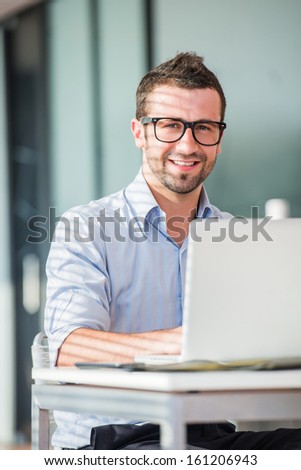 Corporate man posing with laptop at a table