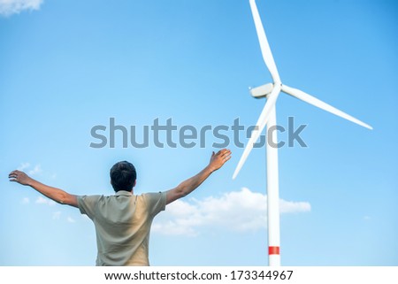 Man standing by wind turbine waving hands