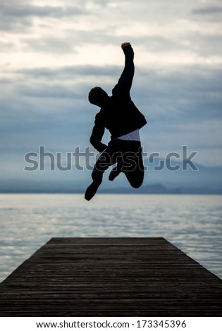 Man celebrating on empty pier jumping
